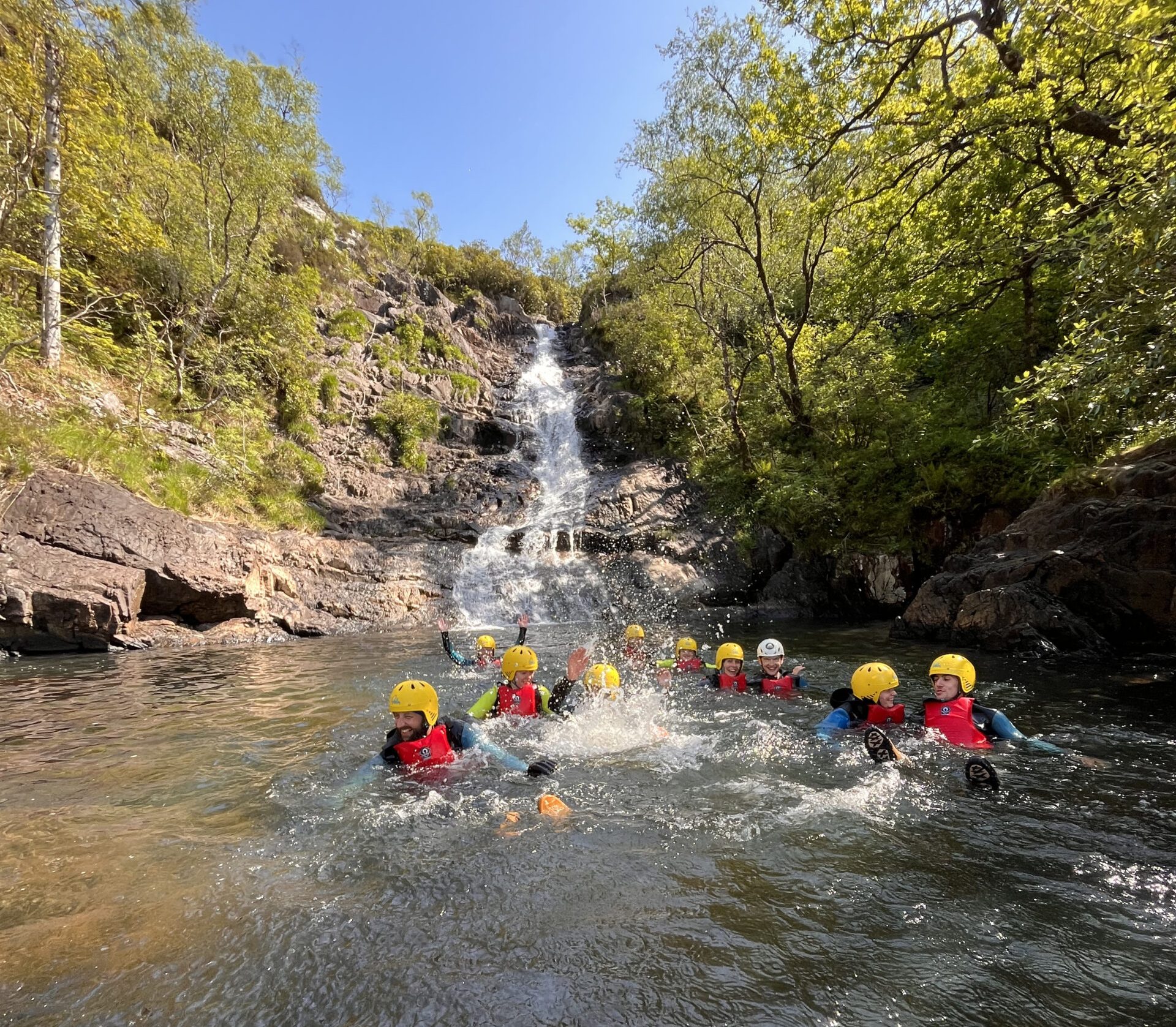 Group Swimming Inchree Falls a group of people riding on the back of a boat in the water