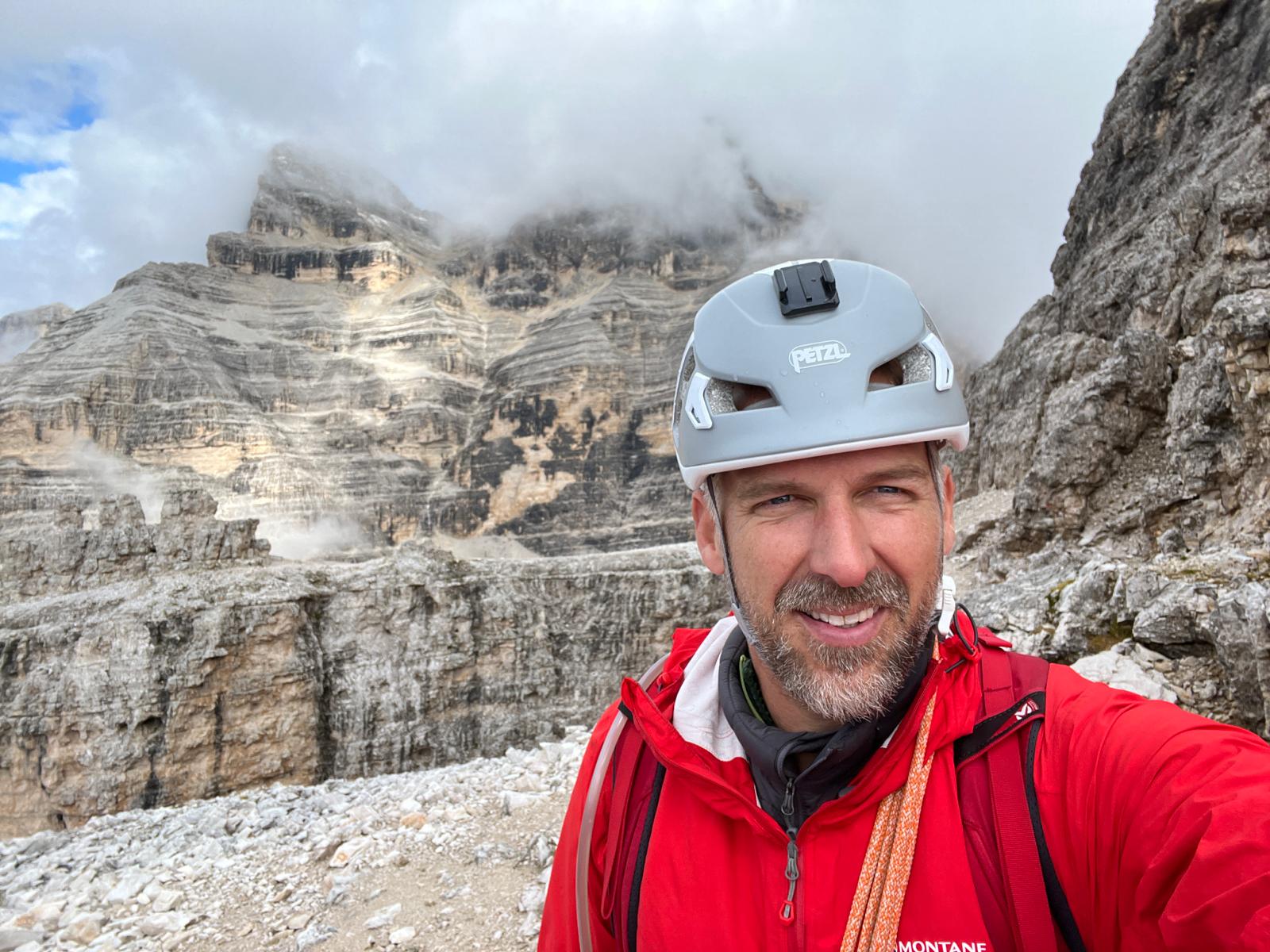 a man wearing a helmet and a mountain in the background