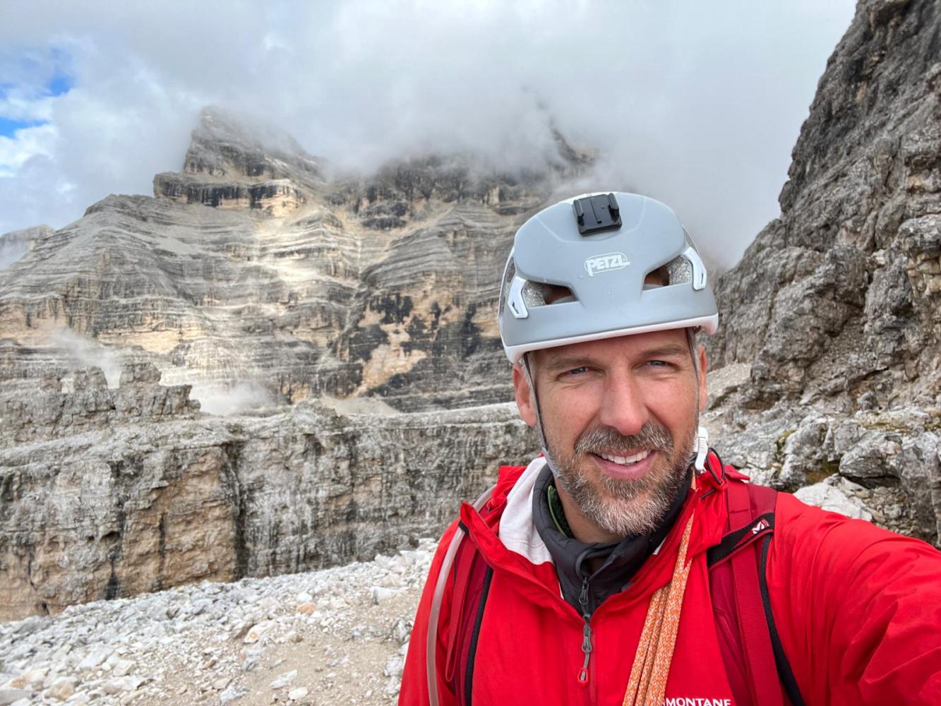 a man wearing a helmet and a mountain in the background